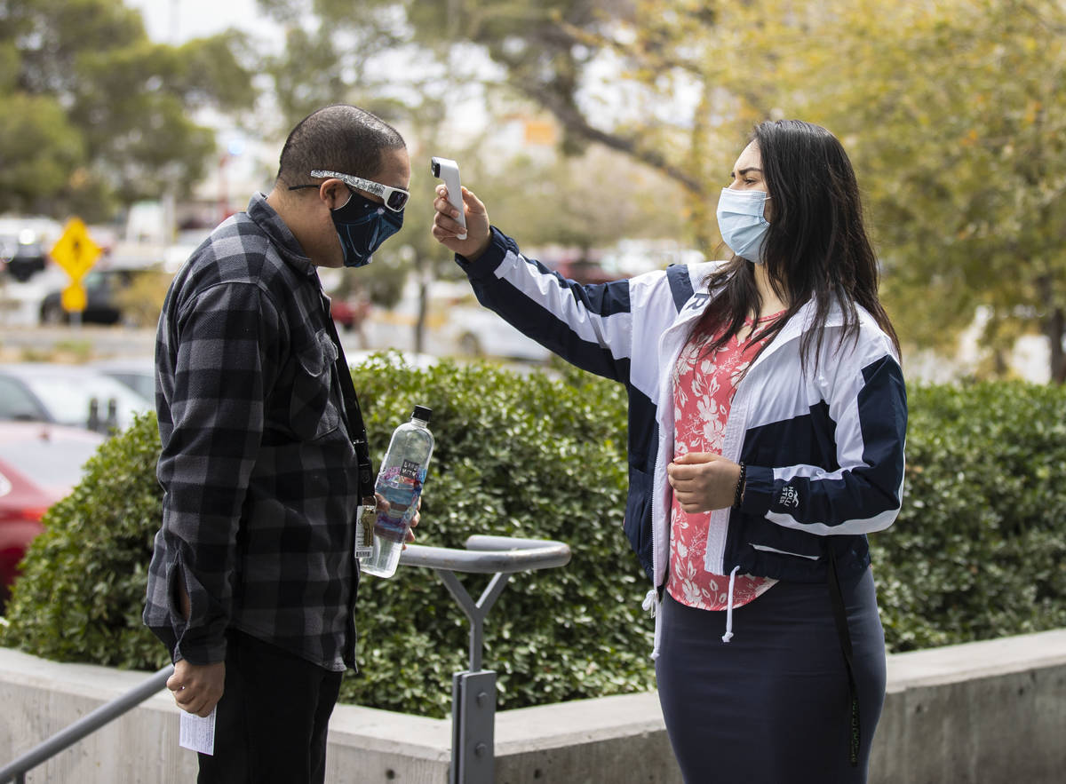 A man gets his temperature taken by Ezabai Coronado, a volunteer, before taking his COVID-19 va ...