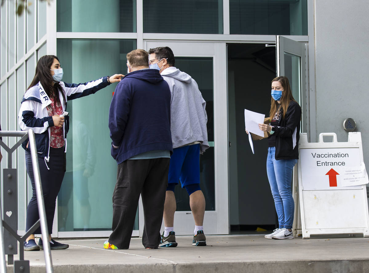 Ezabai Coronado, left, a volunteer, directs people who came to receive a COVID-19 vaccine as An ...