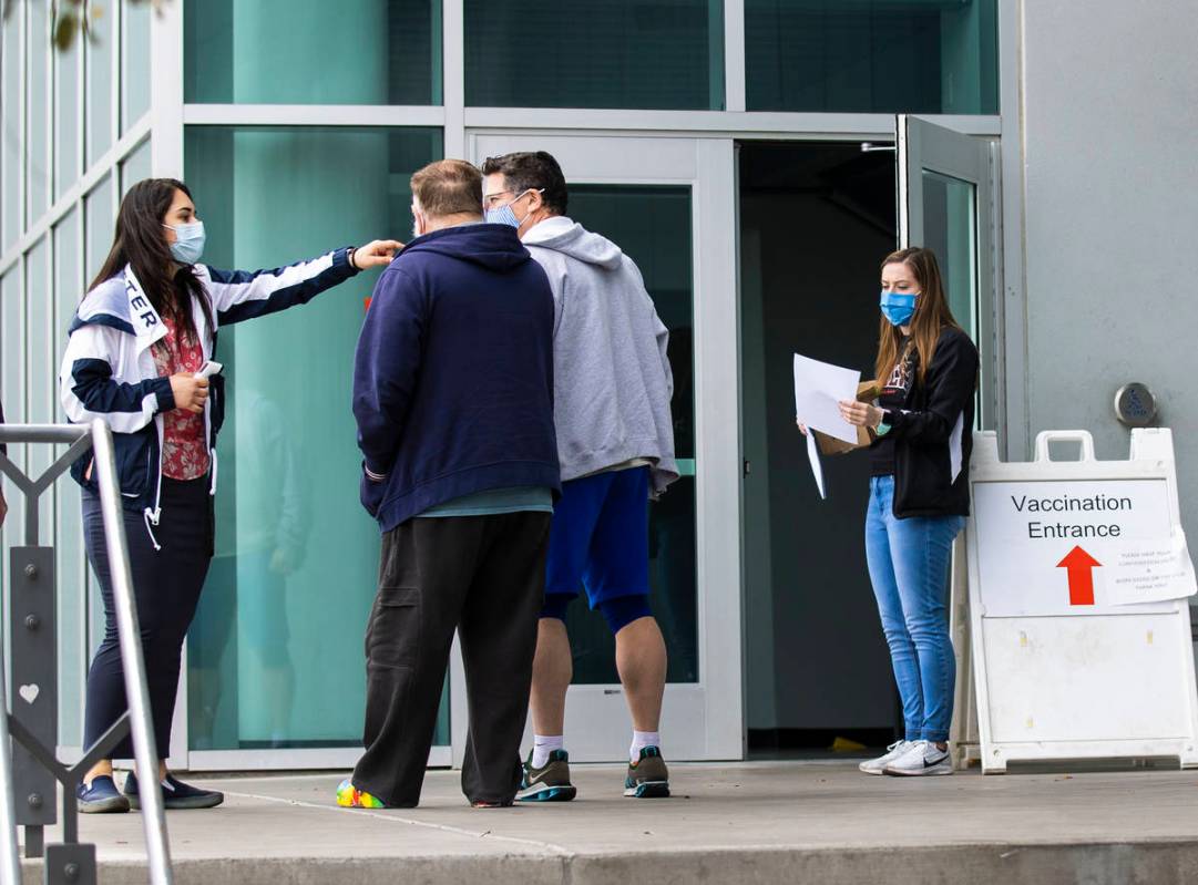 Ezabai Coronado, left, a volunteer, directs people who came to receive a COVID-19 vaccine as An ...