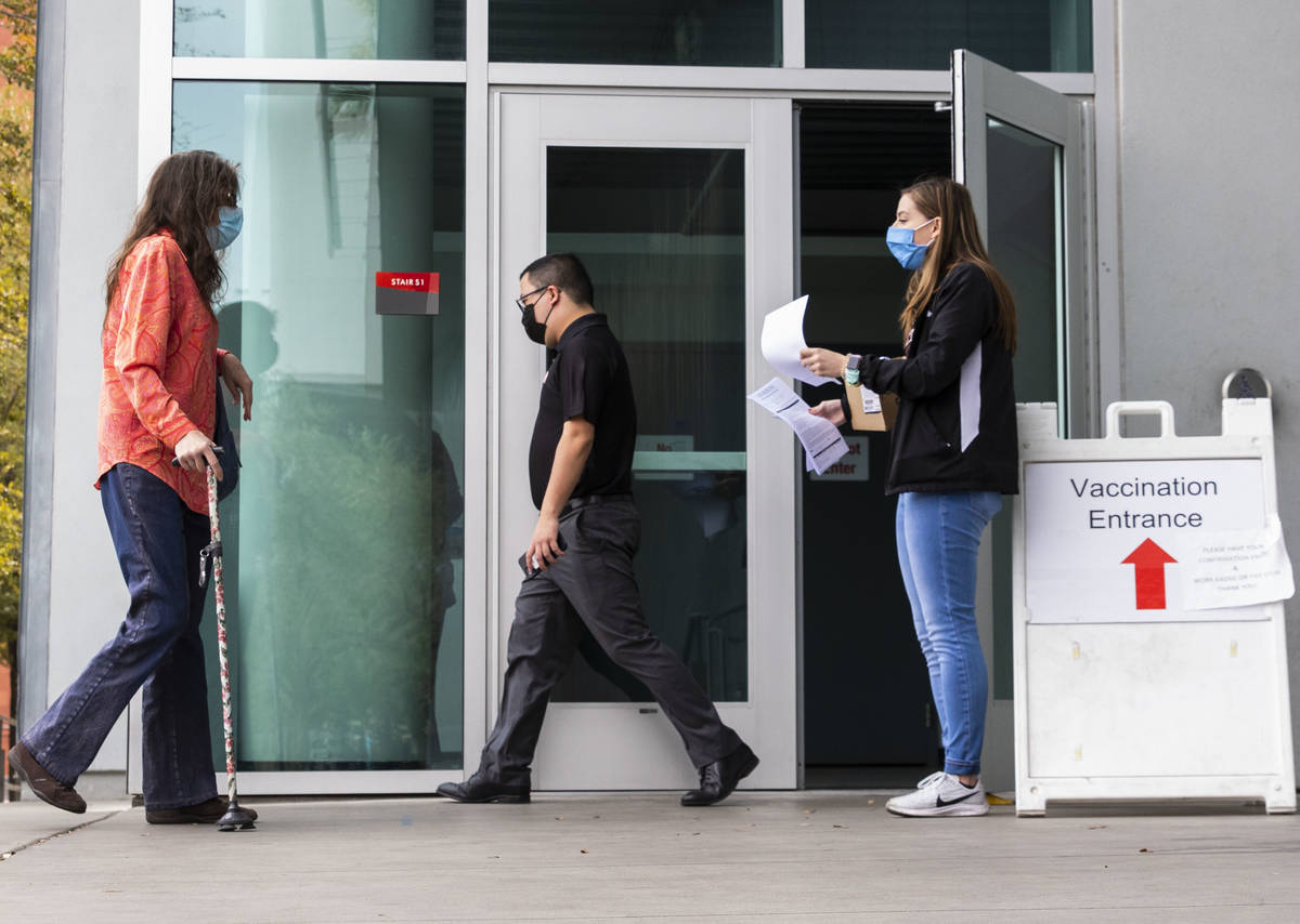 Ann Beck, right, a volunteer, prepares to hand out consent forms to people who came to receive ...