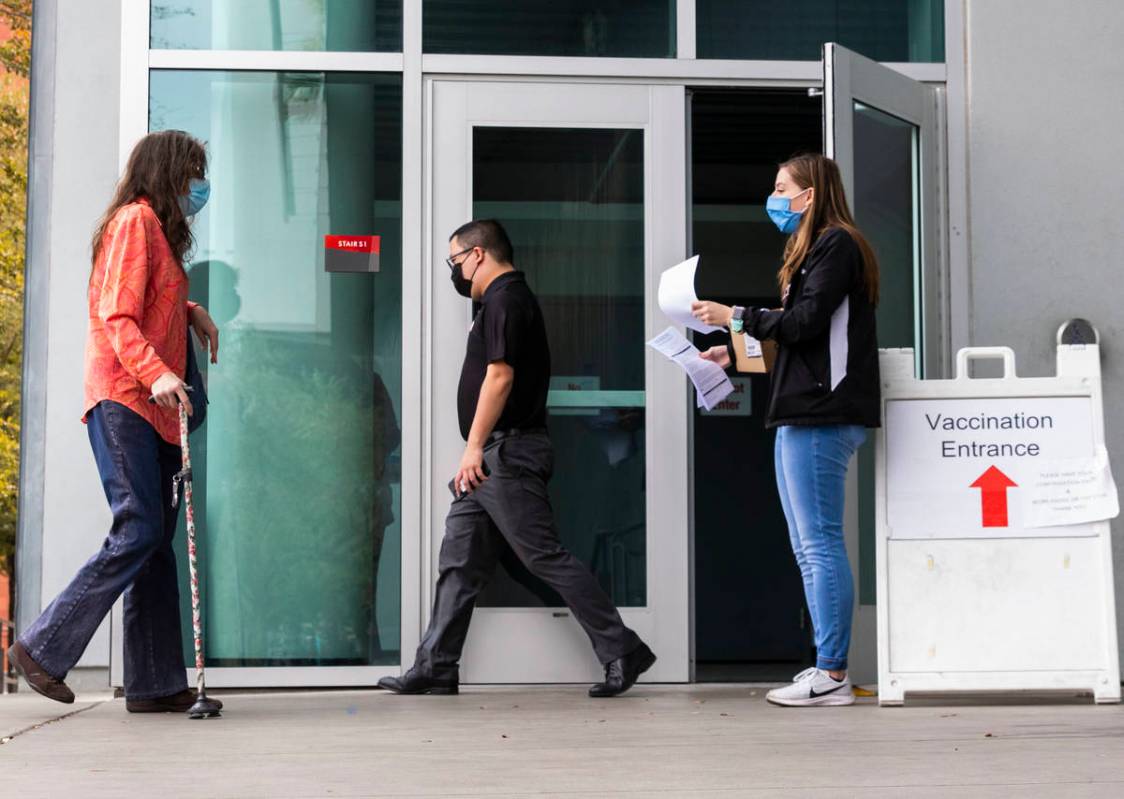 Ann Beck, right, a volunteer, prepares to hand out consent forms to people who came to receive ...