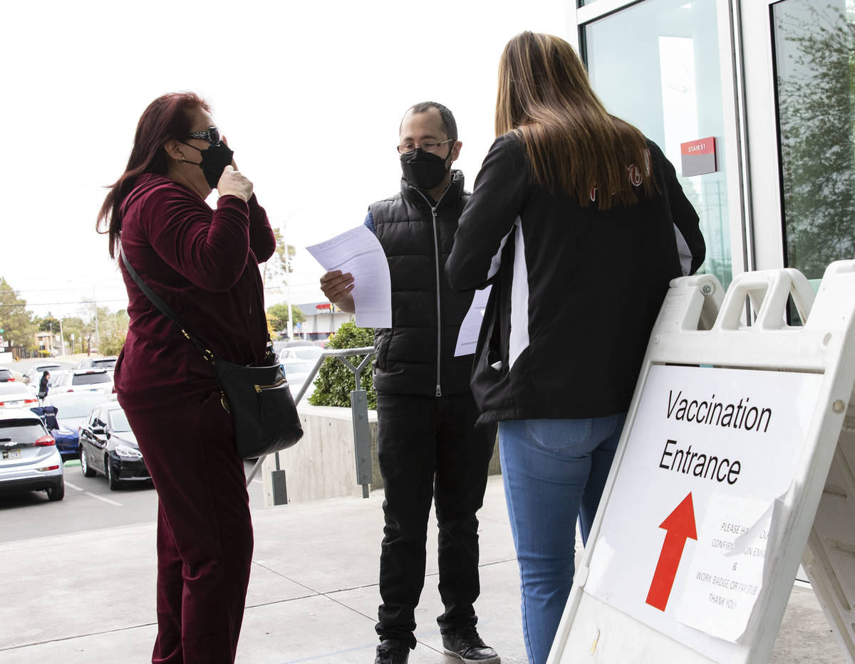 Ann Beck, right, a volunteer, hands out consent forms to people who came to receive a COVID-19 ...