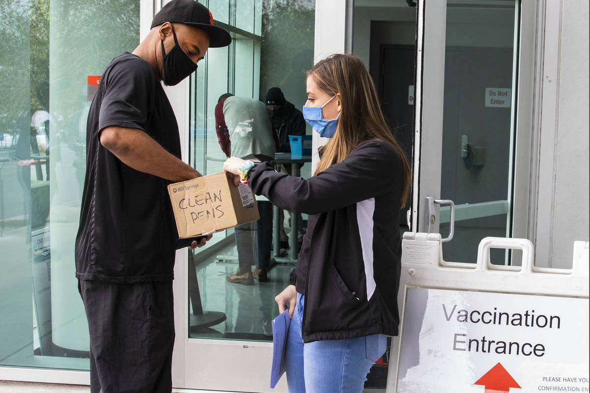 Ann Beck, right, a volunteer, hands out clean pens to a man who came to receive a COVID-19 vacc ...