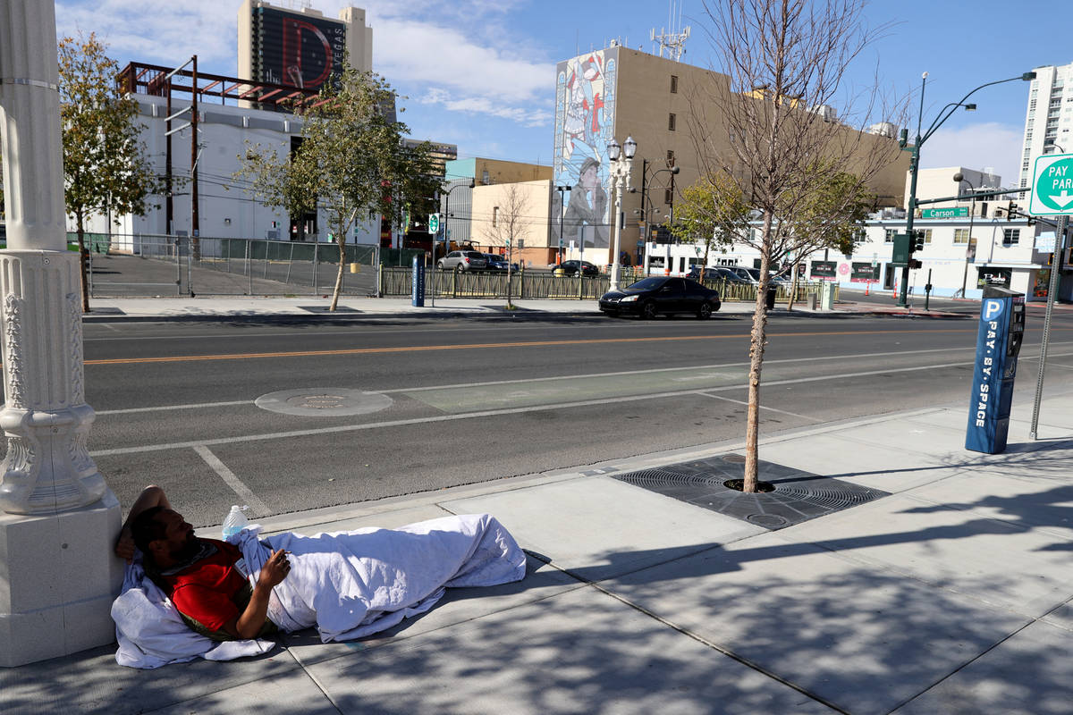 A person sits on the sidewalk on 6th Street near Carson Avenue in downtown Las Vegas Tuesday, M ...