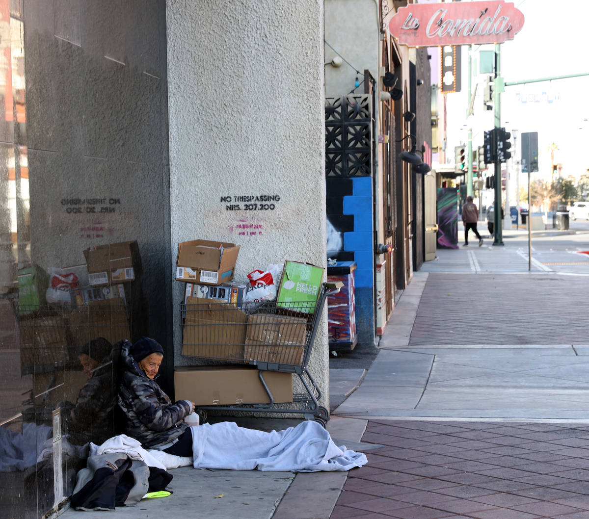 A person sits on the sidewalk on 6th Street near Fremont Street in downtown Las Vegas Tuesday, ...