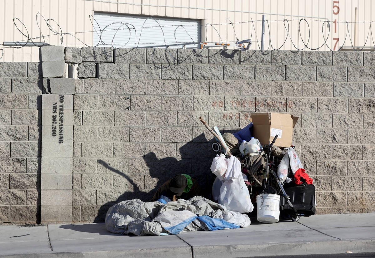 A person sits on the sidewalk on A Street near Owens Avenue in downtown Las Vegas Tuesday, Marc ...