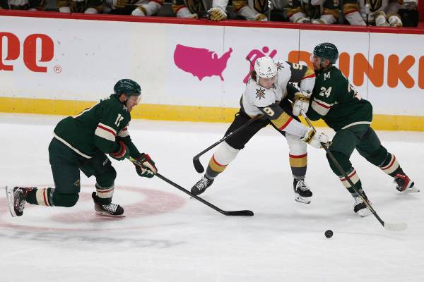 Vegas Golden Knights' Cody Glass (9) tries to gain control of the puck against Minnesota Wild's ...