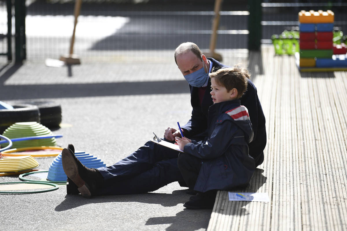 Britain's Prince William talks with a child in the playground during a visit with Kate, Duchess ...