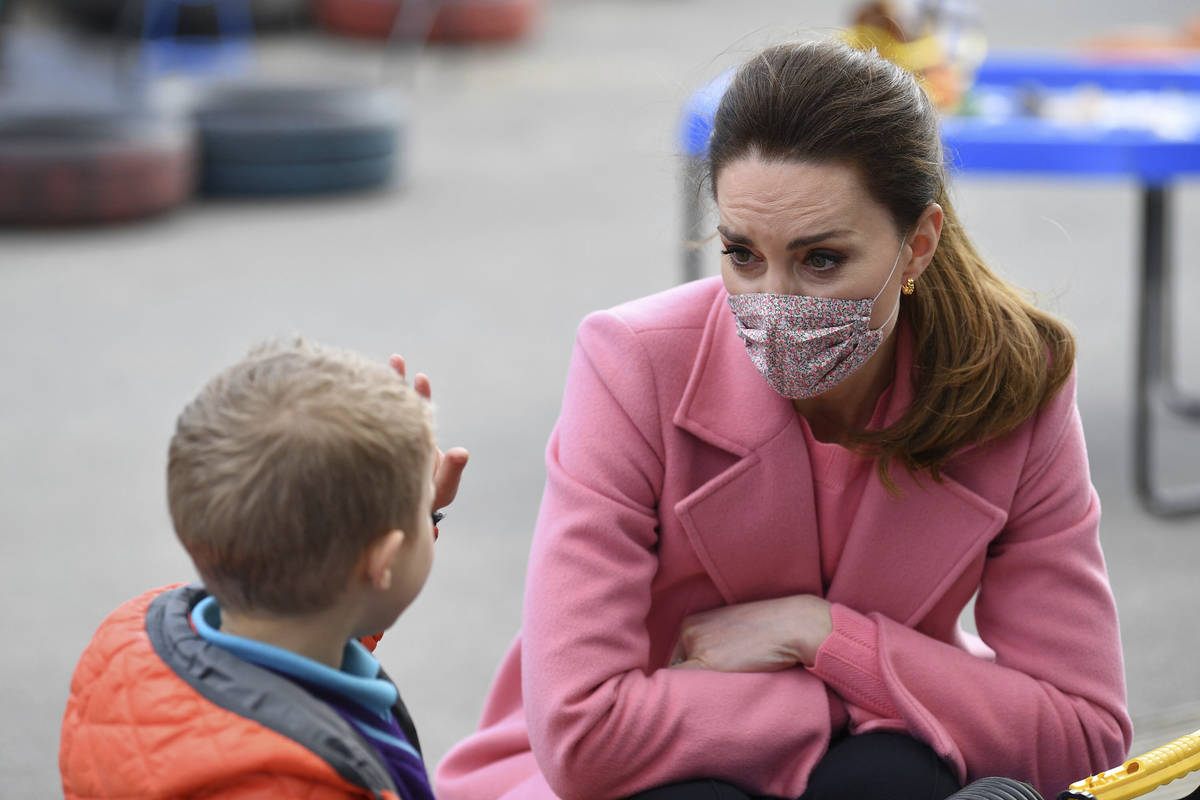 Britain's Kate, Duchess of Cambridge watches as a child holds up five fingers to indicate his a ...