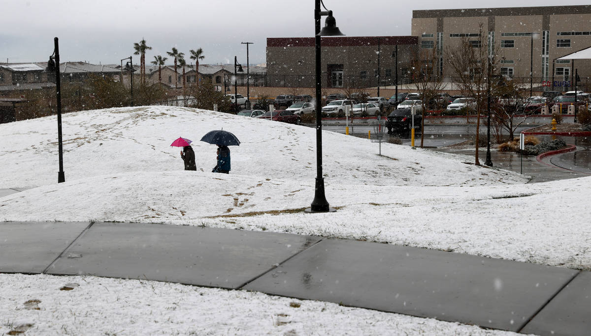 People walk under a light snow at Fox Hill Park in Summerlin in Las Vegas Friday, March 12, 202 ...