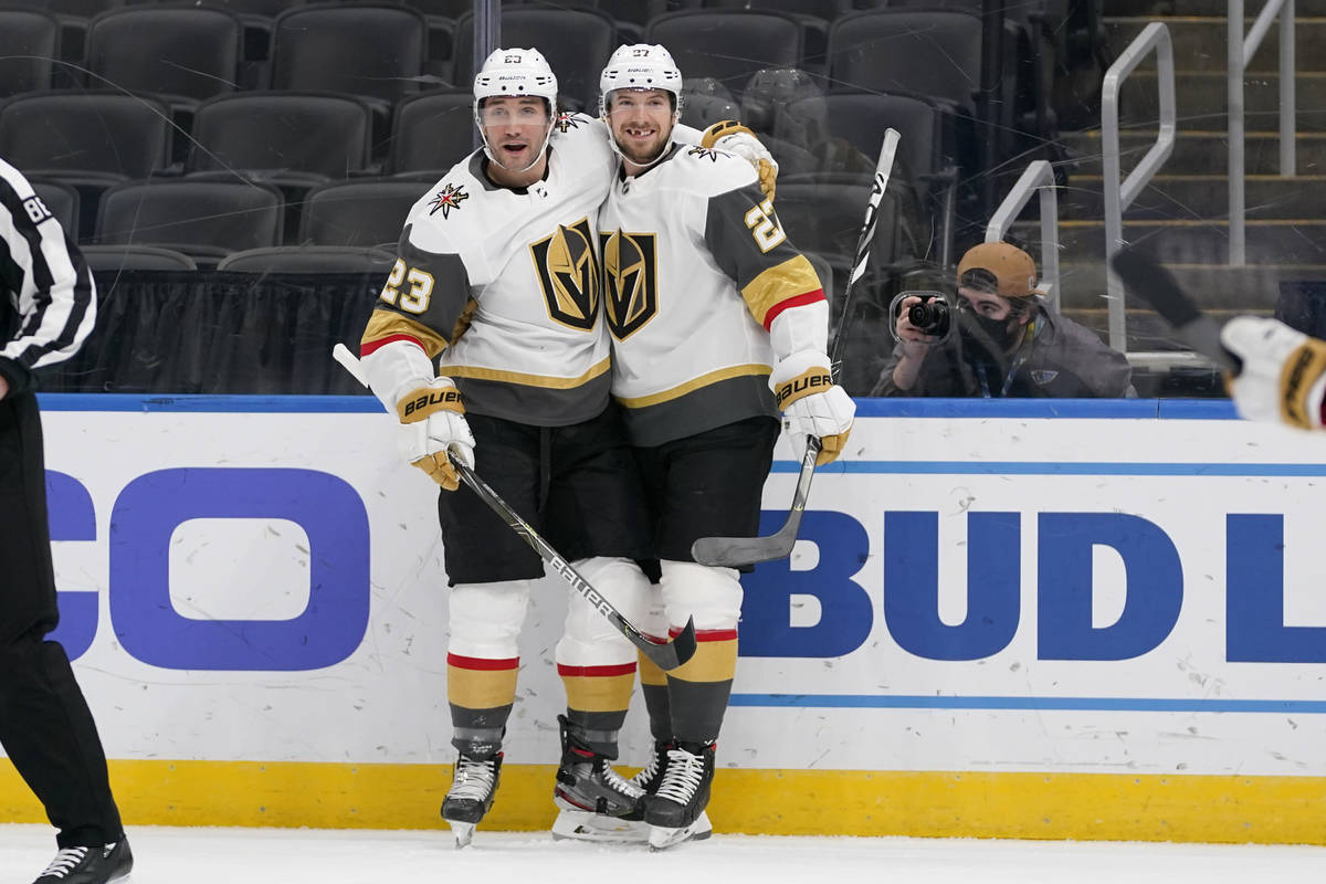 Vegas Golden Knights' Shea Theodore (27) is congratulated by teammate Alec Martinez (23) after ...
