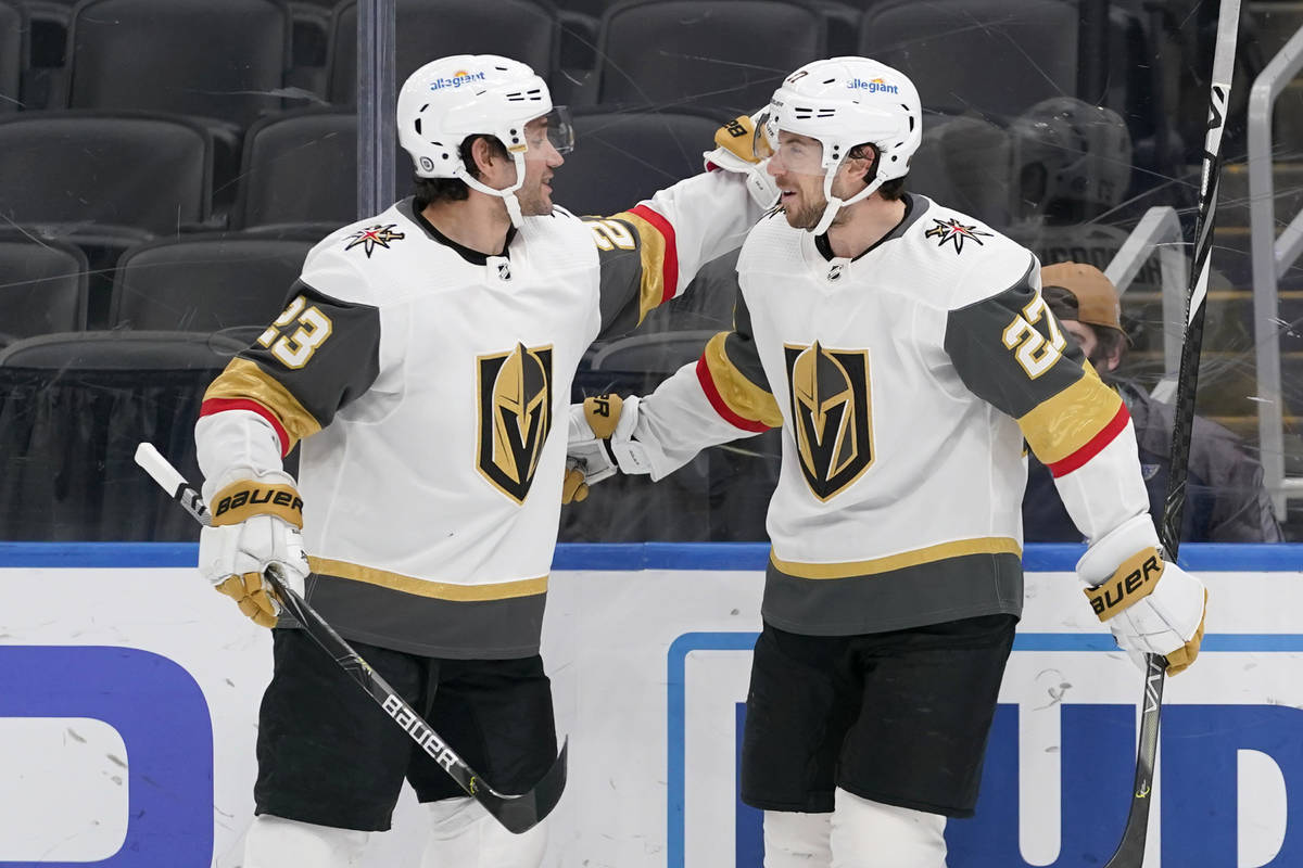 Vegas Golden Knights' Shea Theodore (27) is congratulated by teammate Alec Martinez (23) after ...