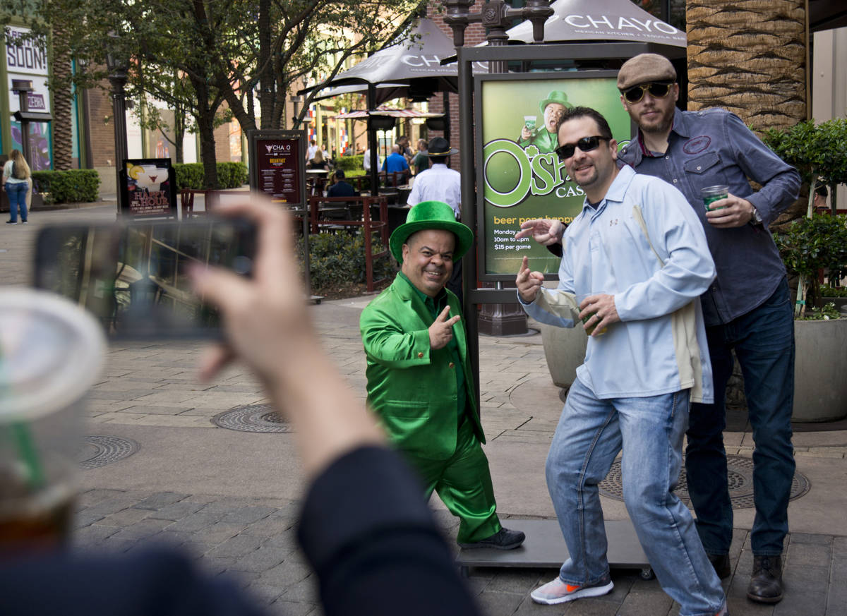 Brian Thomas, O'Sheas casino manager and resident leprechaun, left, takes a photo with brothers ...
