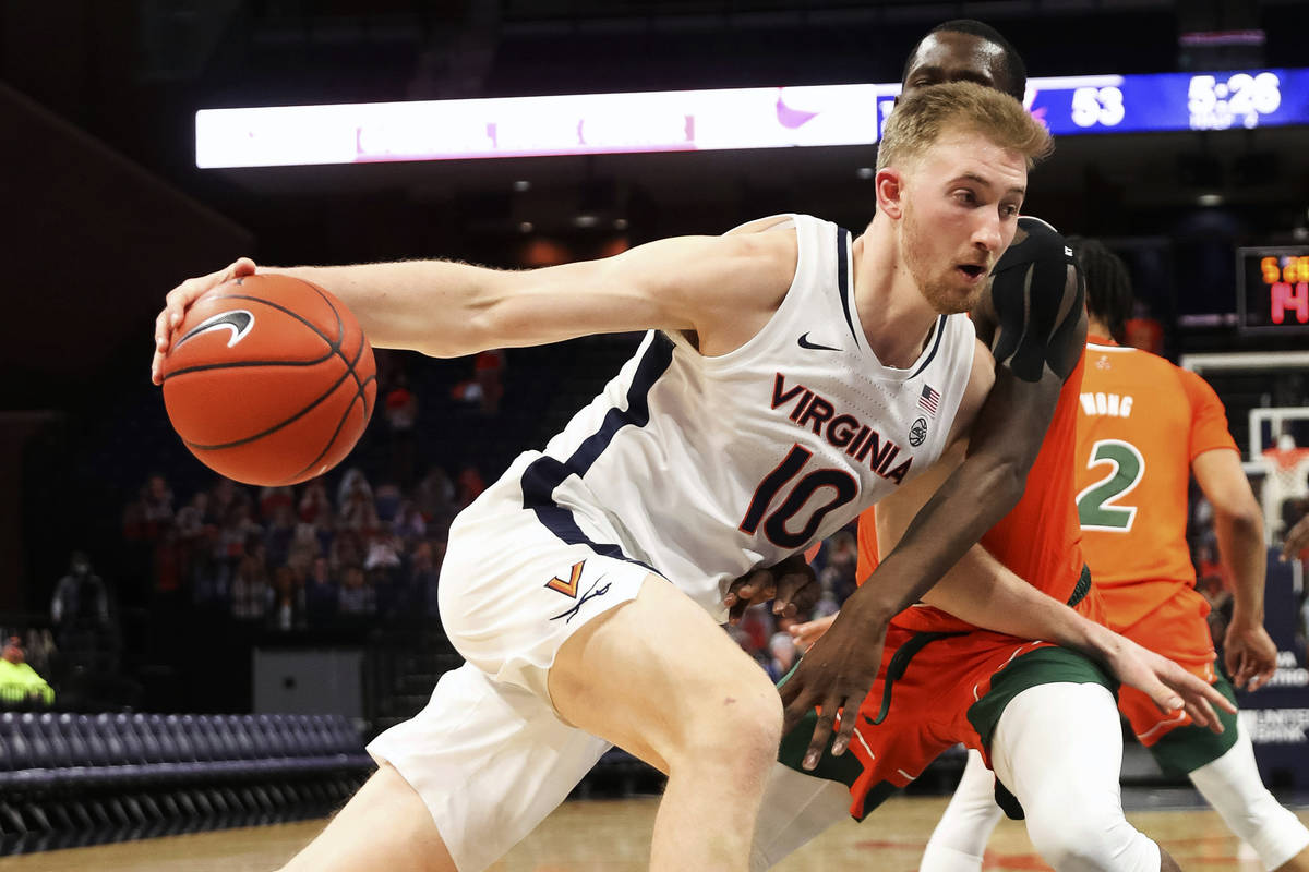 Virginia forward Sam Hauser (10) drives past Miami guard Elijah Olaniyi (4) during an NCAA coll ...