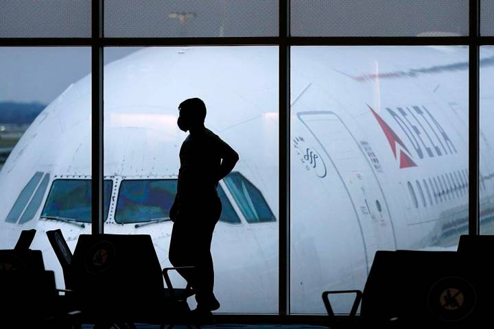 A passenger wears a face mask to help prevent the spread of the new coronavirus as he waits for ...