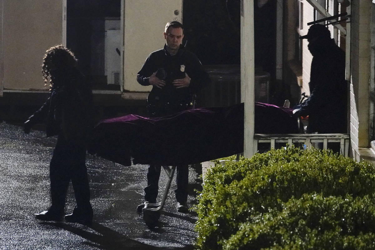 A police officer watches as a body is taken from the Gold Spa massage parlor after a shooting, ...