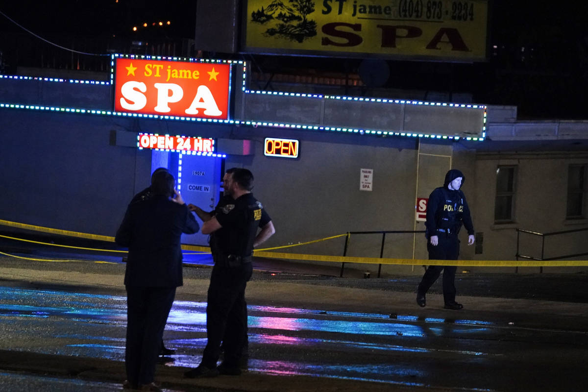 Law enforcement officials confer outside a massage parlor following a shooting on Tuesday, Marc ...