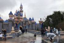 In this March 13, 2020, file photo, visitors take photos at Disneyland in Anaheim, Calif. Close ...