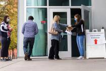 Ann Beck, right, a volunteer, hands out clean pens to people who came to receive a COVID-19 vac ...
