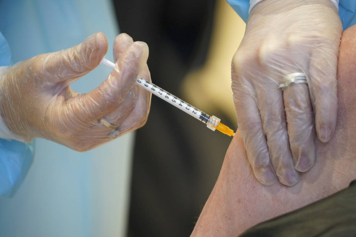 A health worker administers a dose of the AstraZeneca vaccine against COVID-19 to a patient ins ...