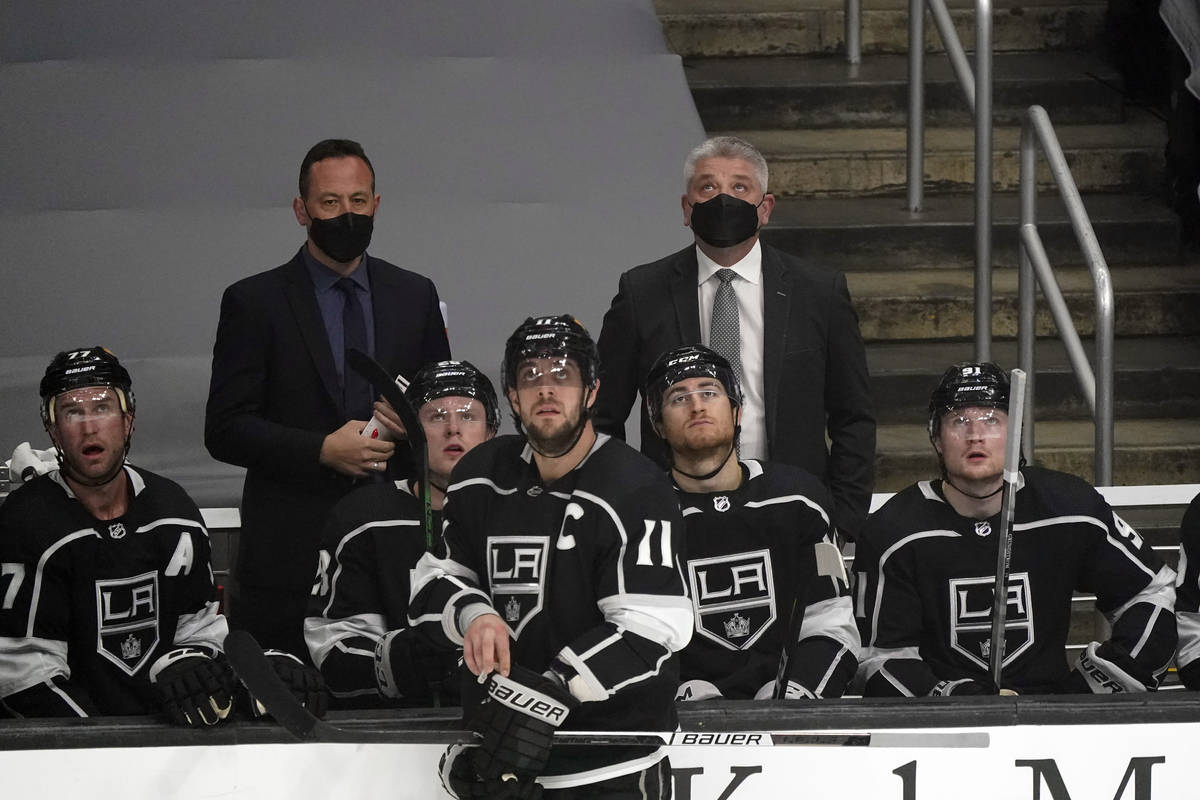 Los Angeles Kings coach Todd McLellan, back right, looks up at the screen during a break in the ...
