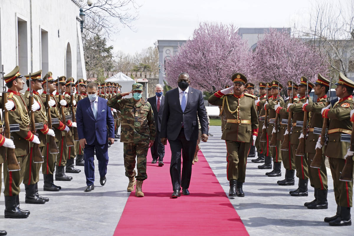 U.S. Defense Secretary Lloyd Austin, center, walks on the red carpet with Acting Afghan Ministe ...