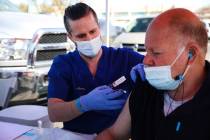 Aaron Storey, left, a physician assistant student from Touro University, administers a COVID-19 ...