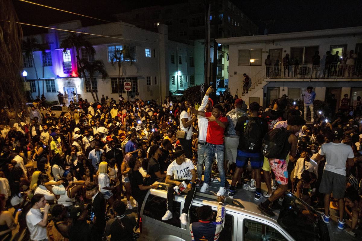 Crowds defiantly gather in the street while a speaker blasts music an hour past curfew in Miami ...