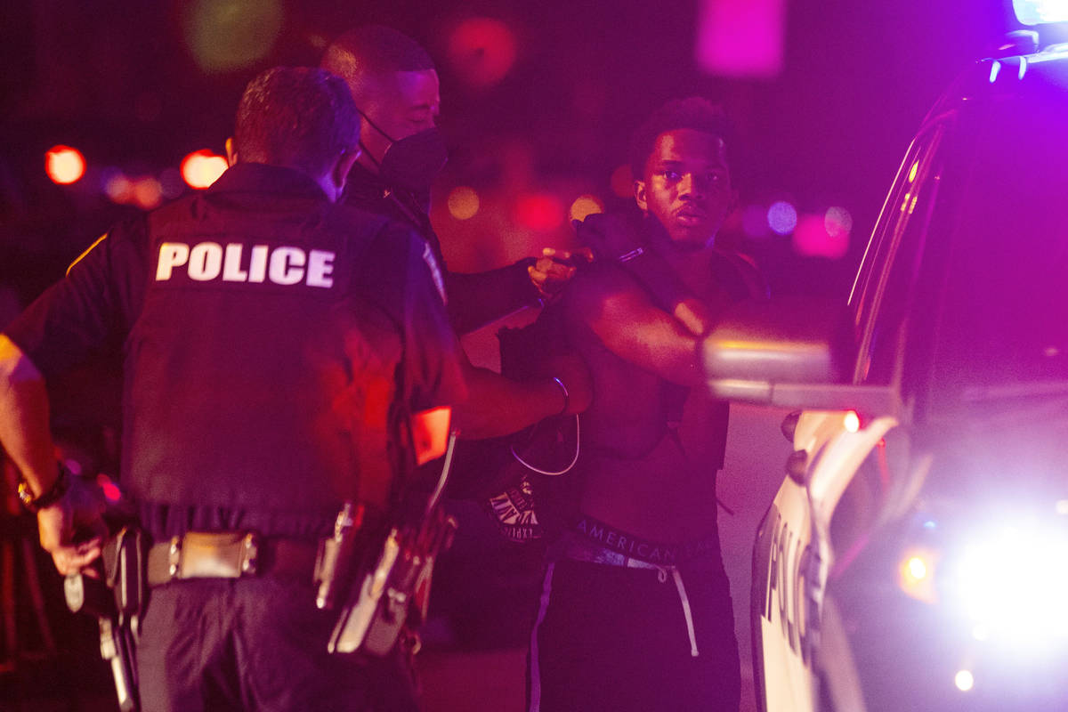 A man is arrested while out a few hours past curfew in Miami Beach, Fla., on Sunday, March 21, ...