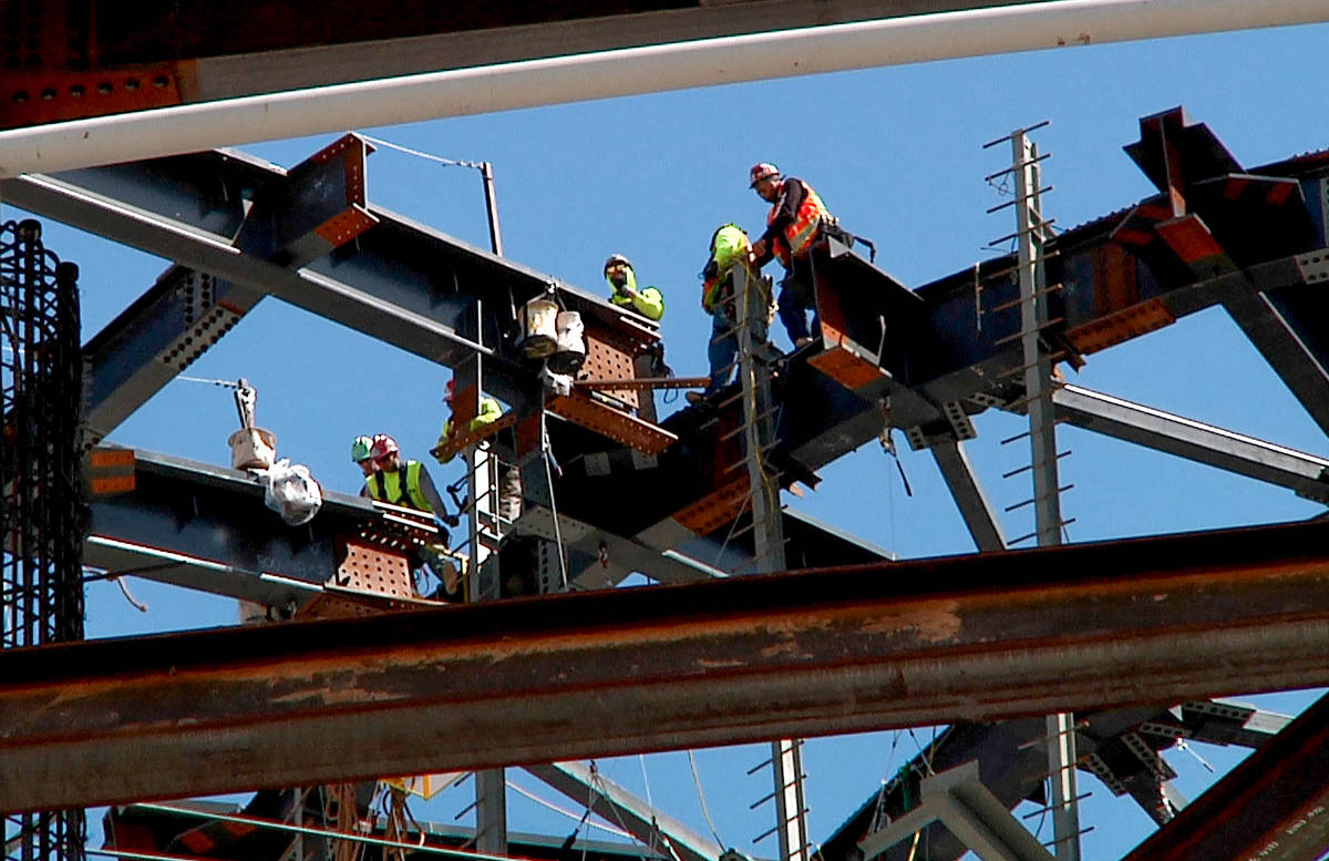 Workers match a 100 ton roof truss to the central compression ring on top of a 285-foot, 677-to ...