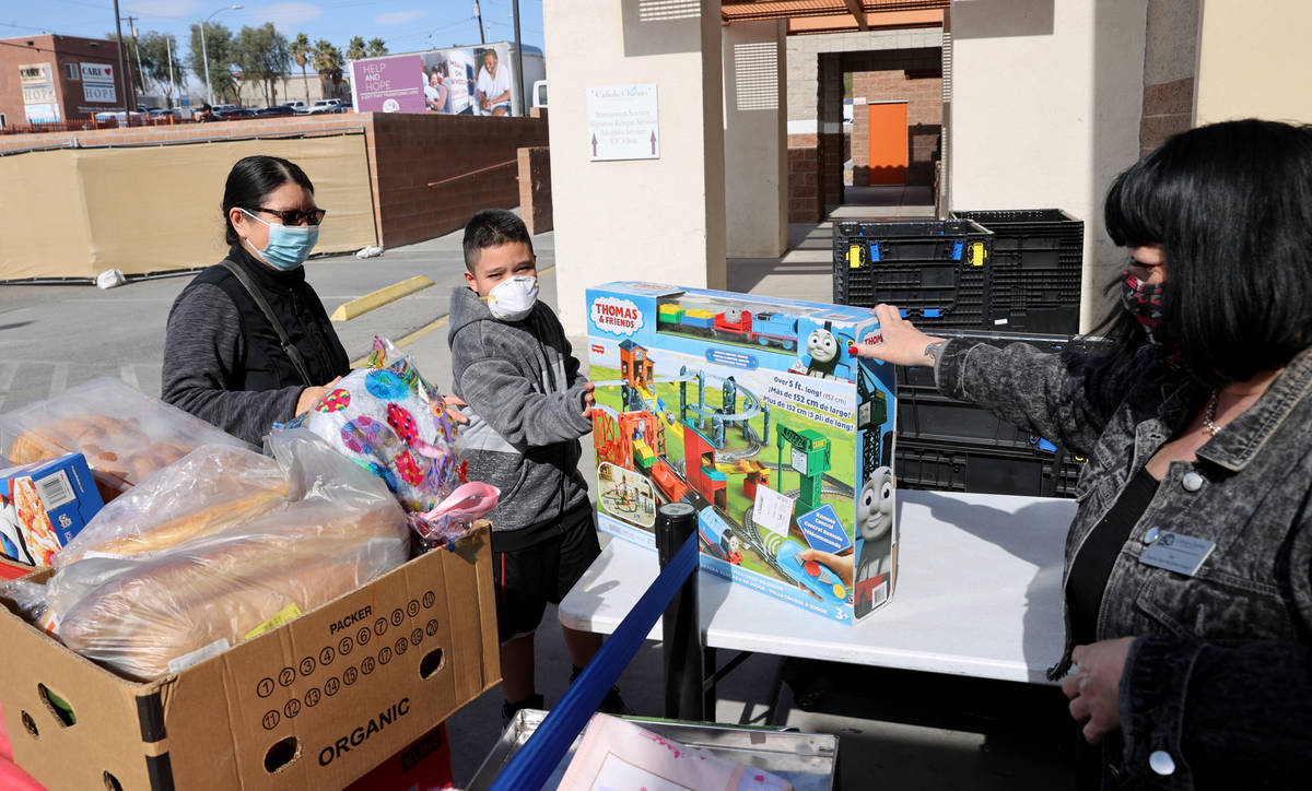 Food Pantry Manager Sue Kurland adds a toy to the food distribution for Jeremy Galindo, 10, and ...