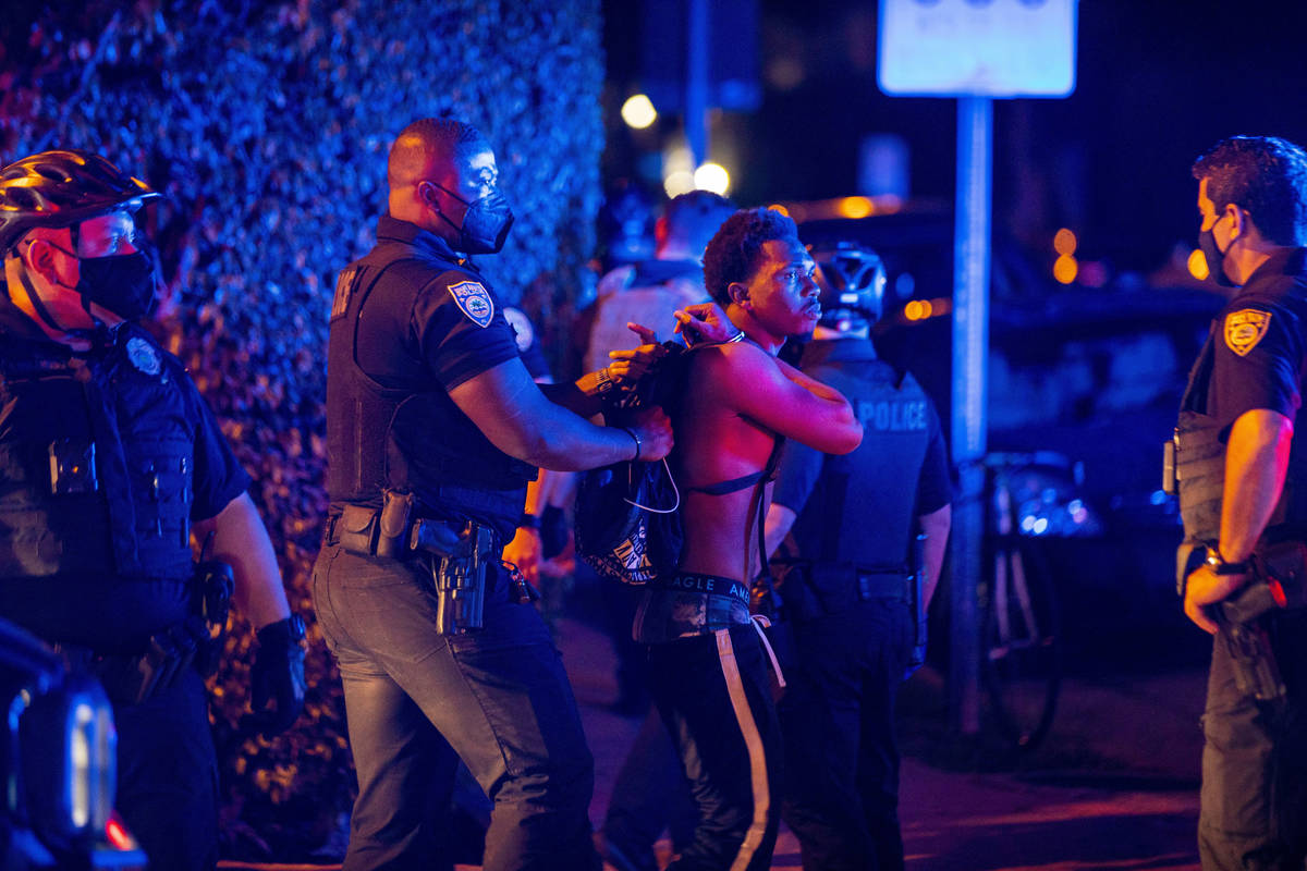 A man is arrested while out a few hours past curfew in Miami Beach, Fla., on March 21. Miami Be ...