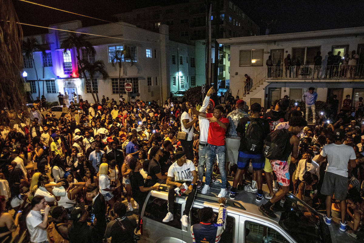 Crowds defiantly gather in the street while a speaker blasts music an hour past curfew in Miami ...