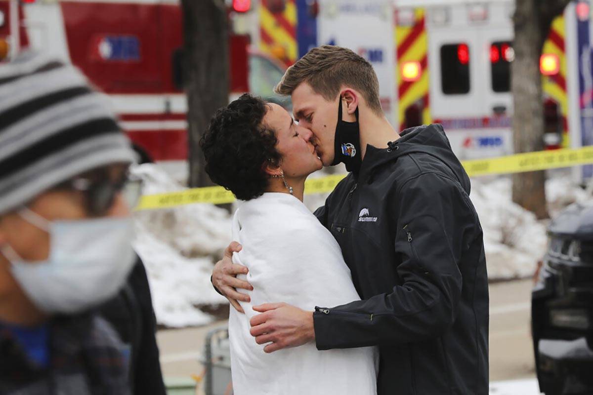 A man and woman kiss near the scene of a mass shooting in a King Soopers grocery store, Monday, ...