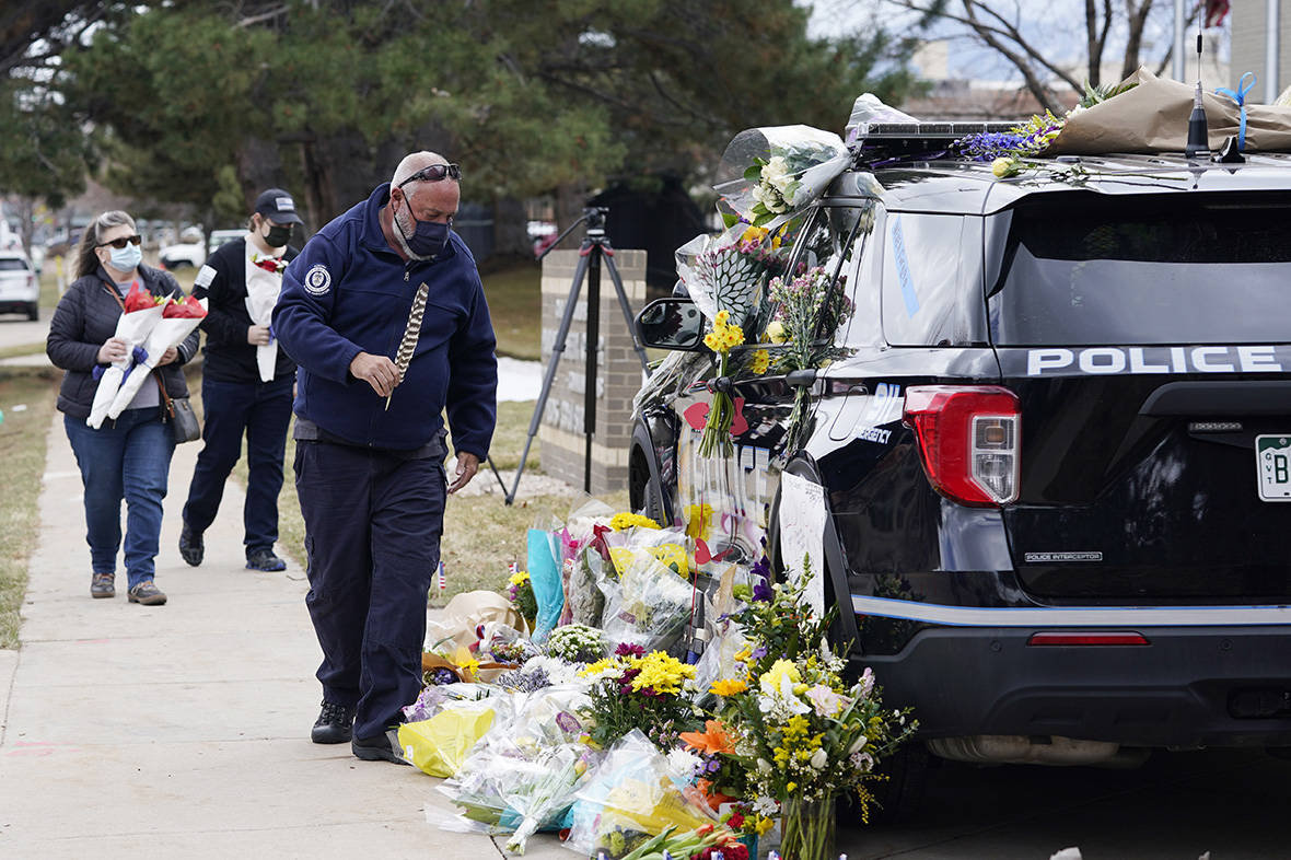Residents leave bouquets on a police cruiser parked outside the Boulder Police Department after ...