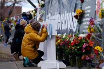 Mourners sign crosses, Tuesday, March 23, 2021, placed in honor of the victims, along a fence p ...