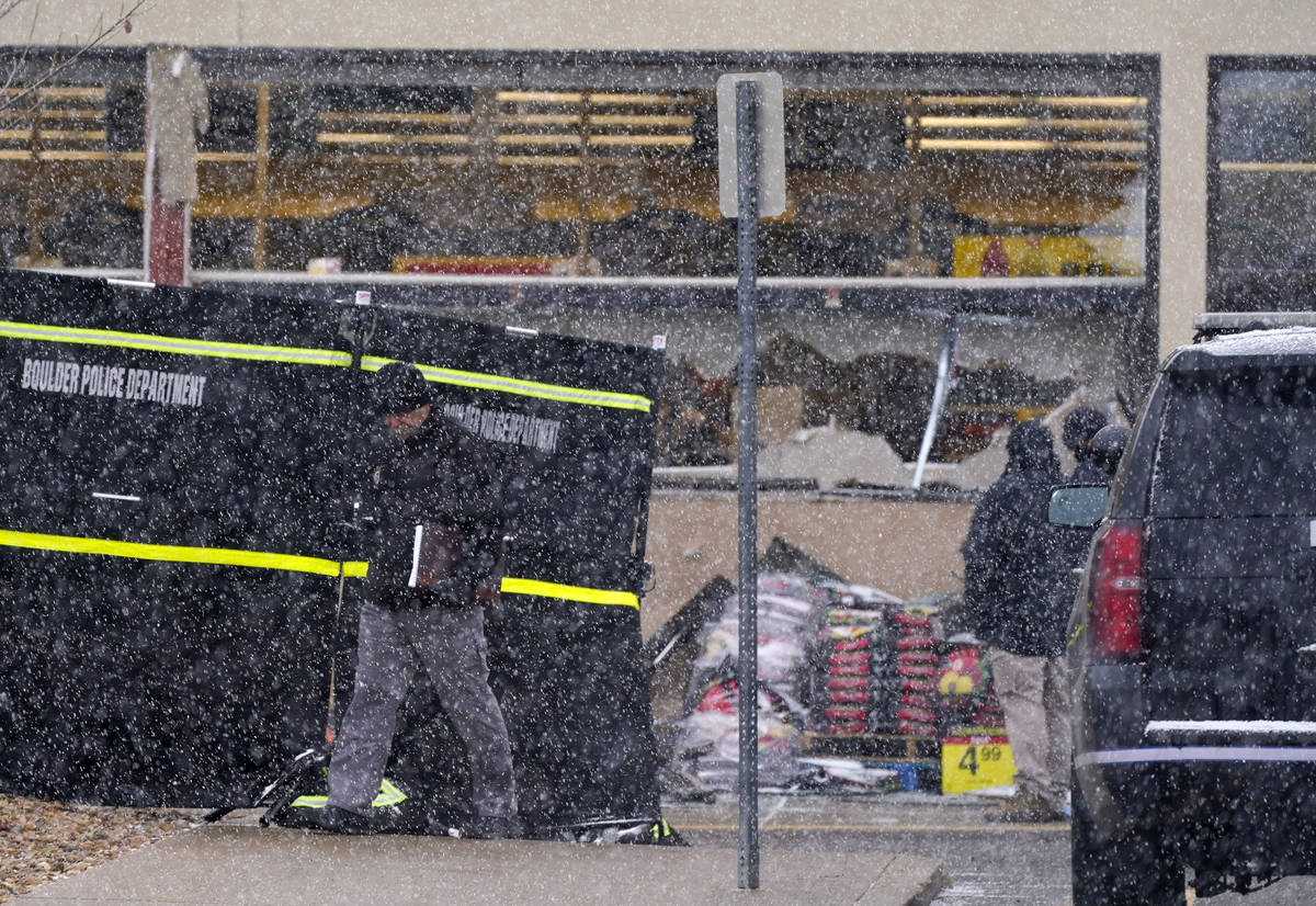 A snow squall envelops investigators as they collect evidence around the parking lot where a ma ...