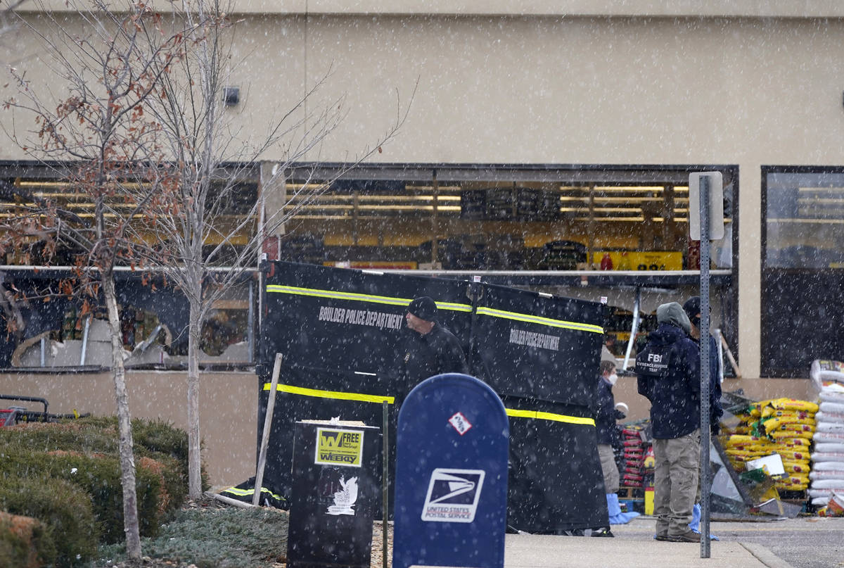Snow falls as investigators continue to collect evidence in the parking lot where a mass shooti ...