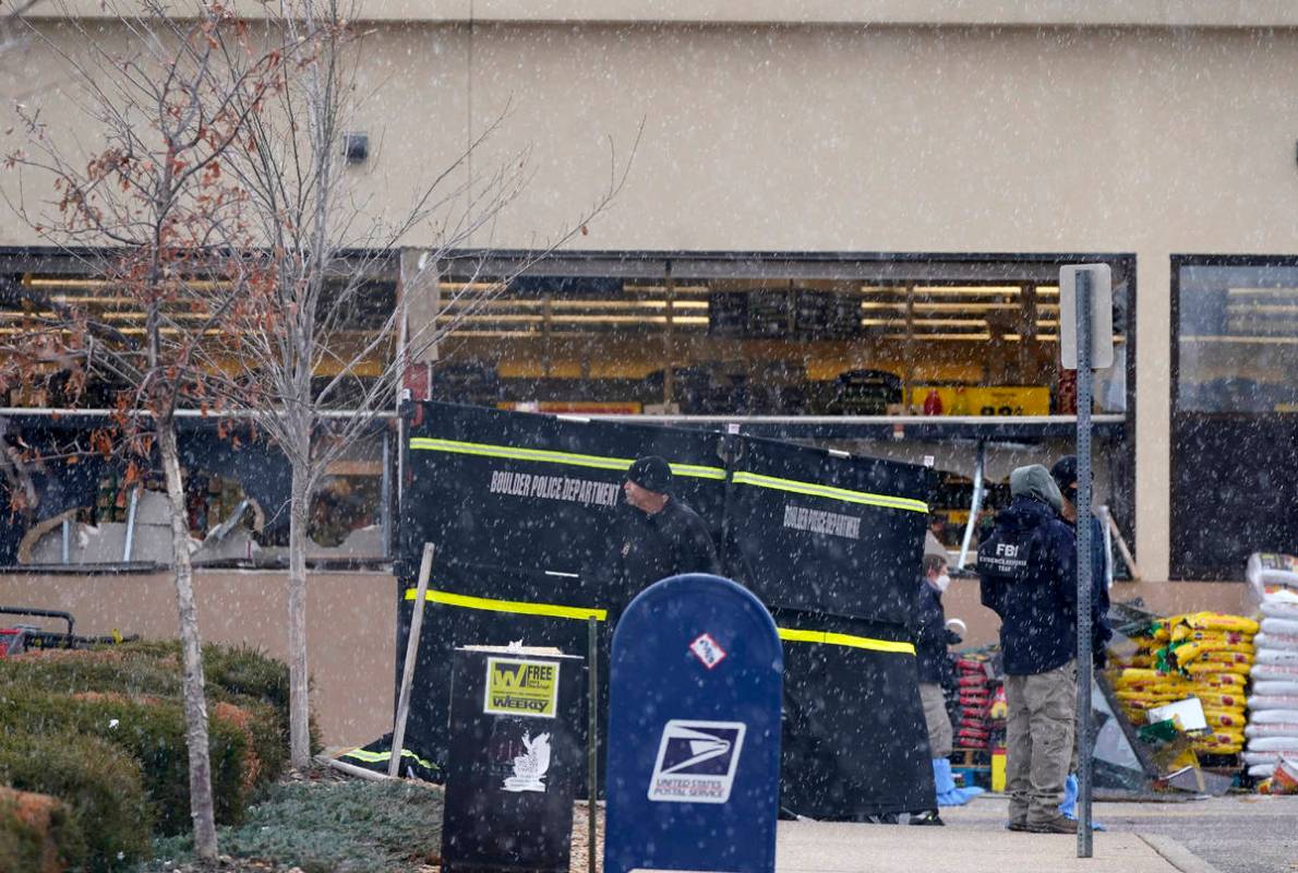 Snow falls as investigators continue to collect evidence in the parking lot where a mass shooti ...