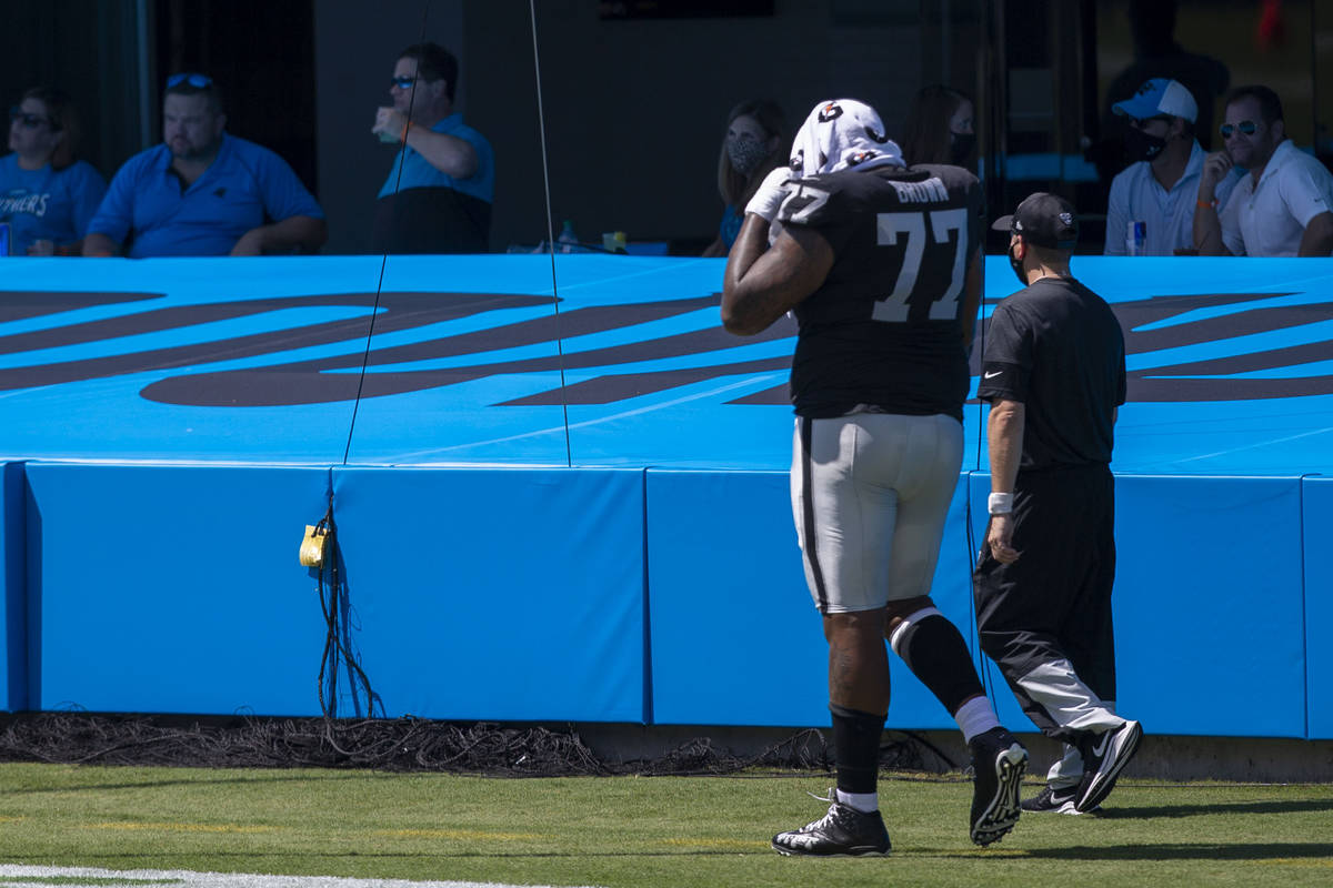 Las Vegas Raiders offensive tackle Trent Brown (77) walks off the field with a trainer after th ...