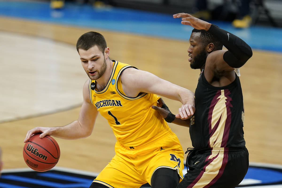 Michigan center Hunter Dickinson, left, drives past Florida State forward RaiQuan Gray, right, ...