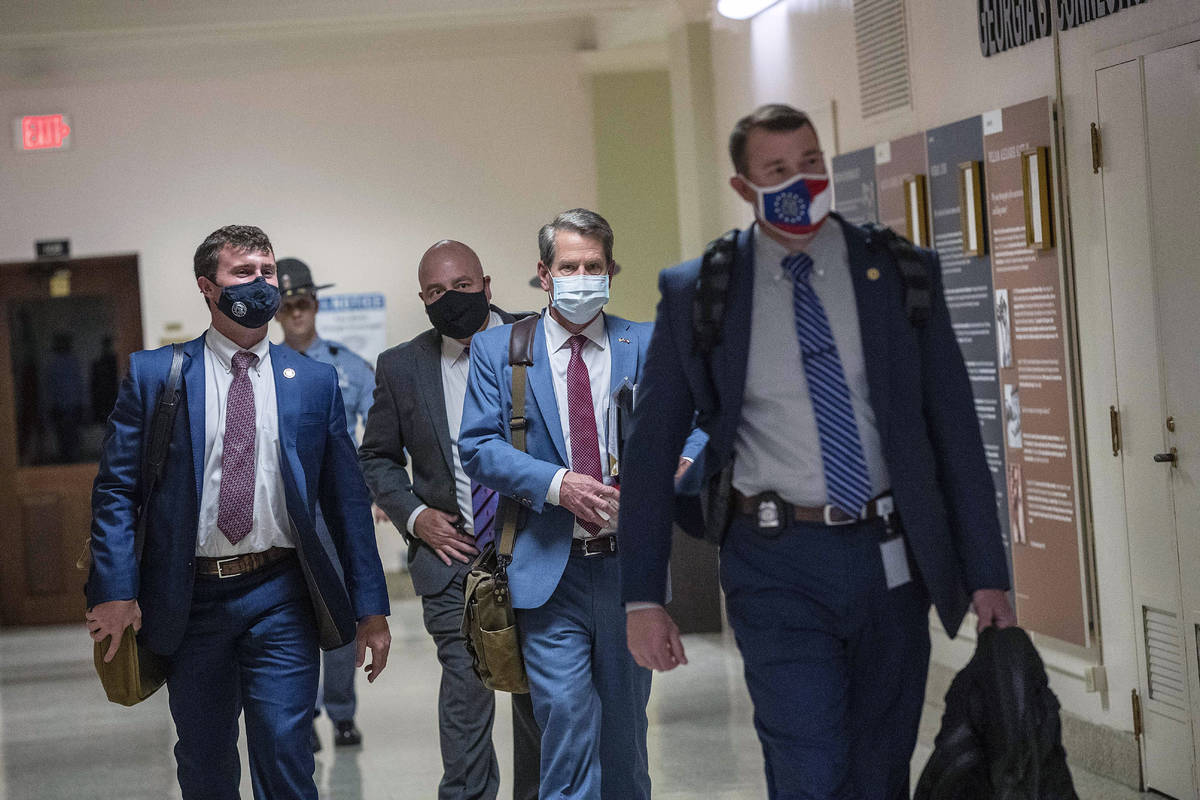 Georgia Gov. Brian Kemp, second from right, leaves the Georgia State Capitol Building after he ...