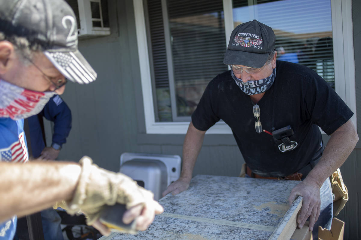 Jeff Hughes, right, holds a countertop steady as Allan Kennedy cuts a hold for the sink while t ...
