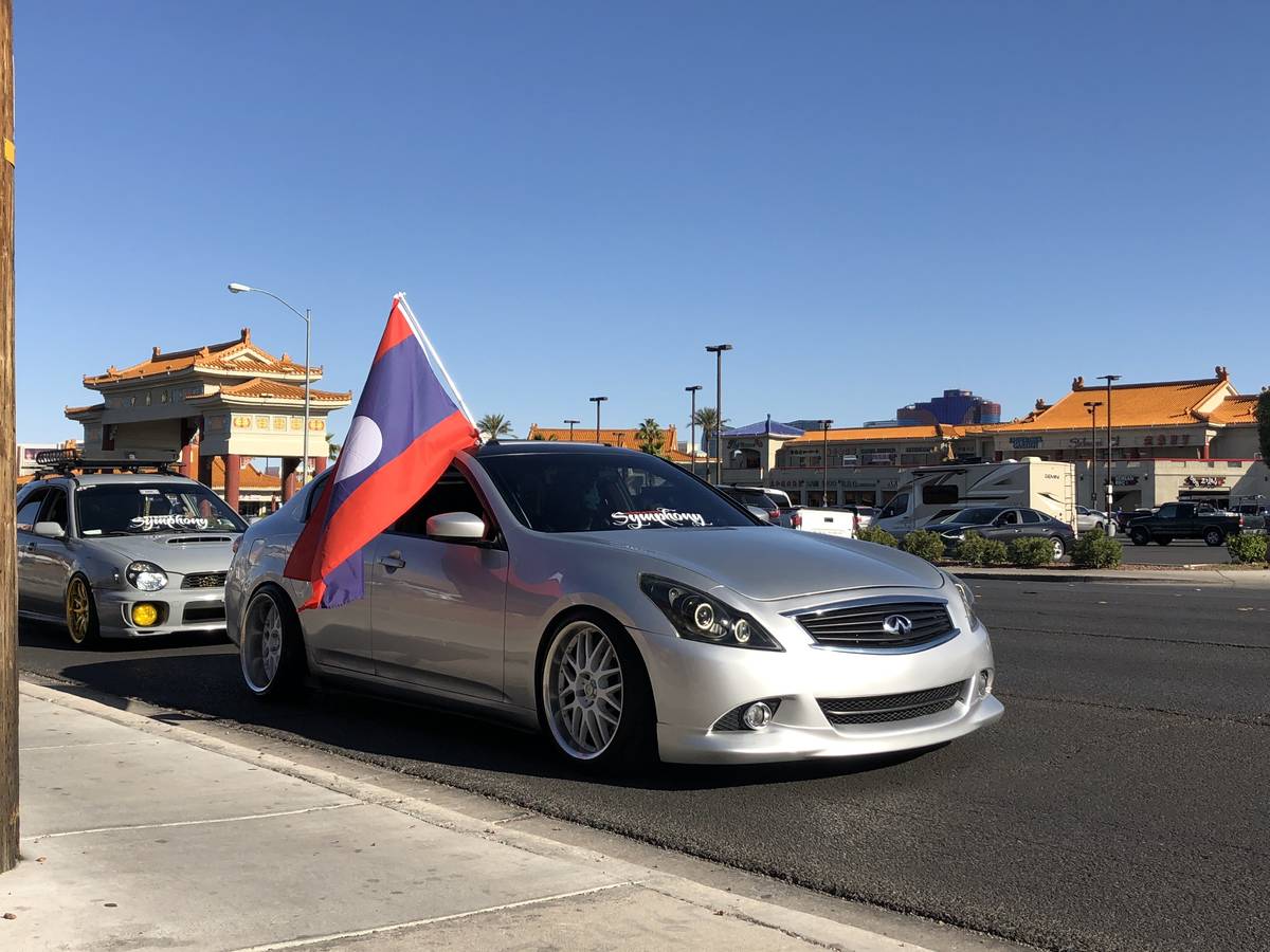 A car drives past Chinatown businesses displaying the Laos flag during the "Las Vegas Cruise fo ...