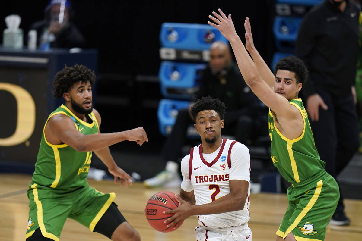 Southern California guard Tahj Eaddy (2) drives between Oregon guard LJ Figueroa, left, and gua ...
