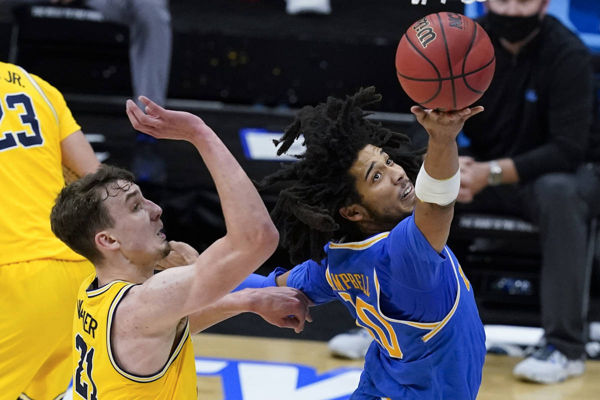 UCLA guard Tyger Campbell drives to the basket in front of Michigan guard Franz Wagner, left, d ...