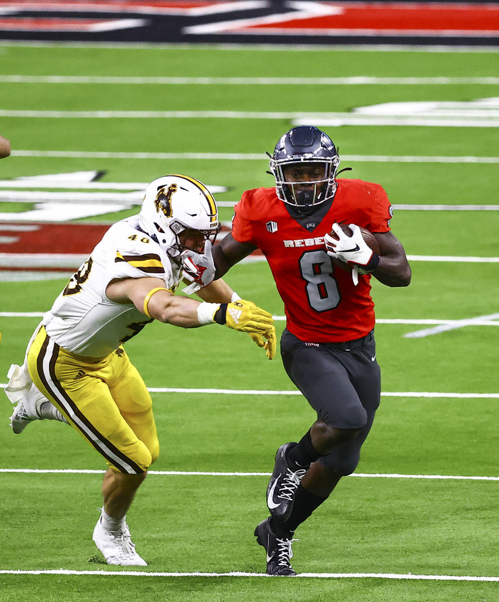 UNLV Rebels running back Charles Williams (8) runs the ball under pressure from Wyoming Cowboys ...