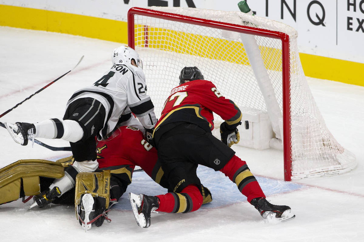 Kings defenseman Christian Wolanin (24) and Golden Knights defenseman Shea Theodore (27) fall i ...