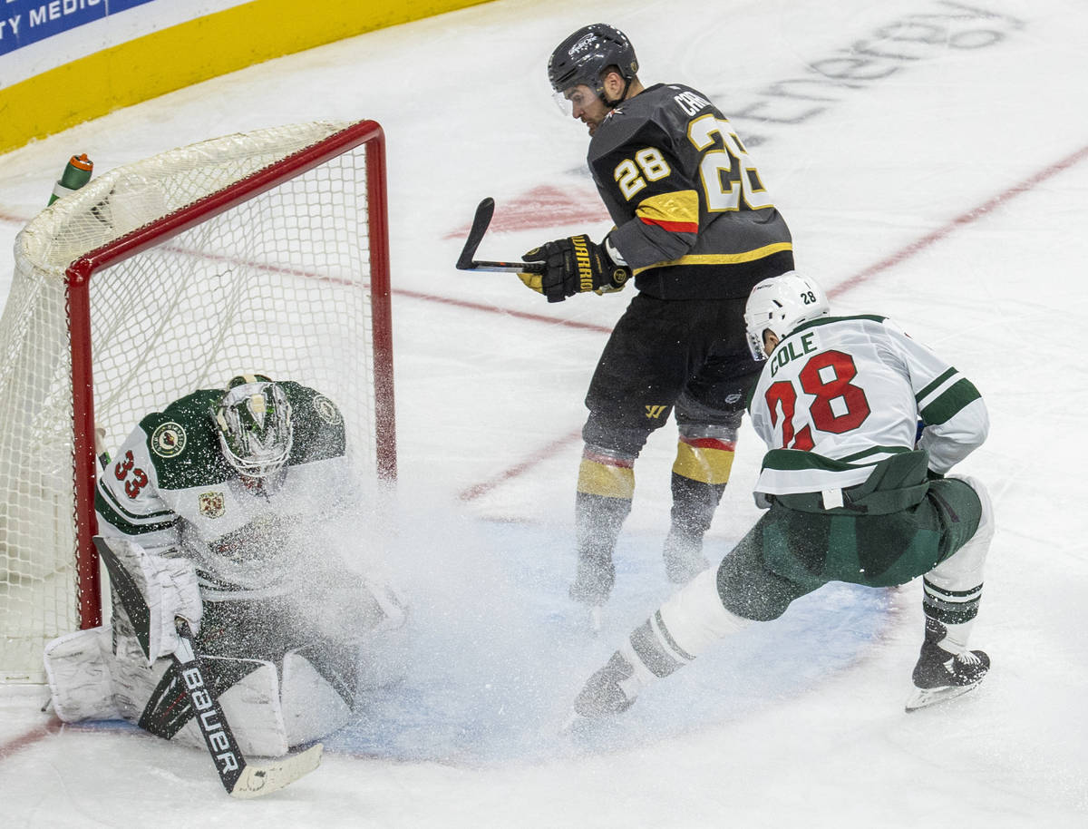 Minnesota Wild goaltender Cam Talbot (33) traps a shot on goal by a driving Golden Knights left ...