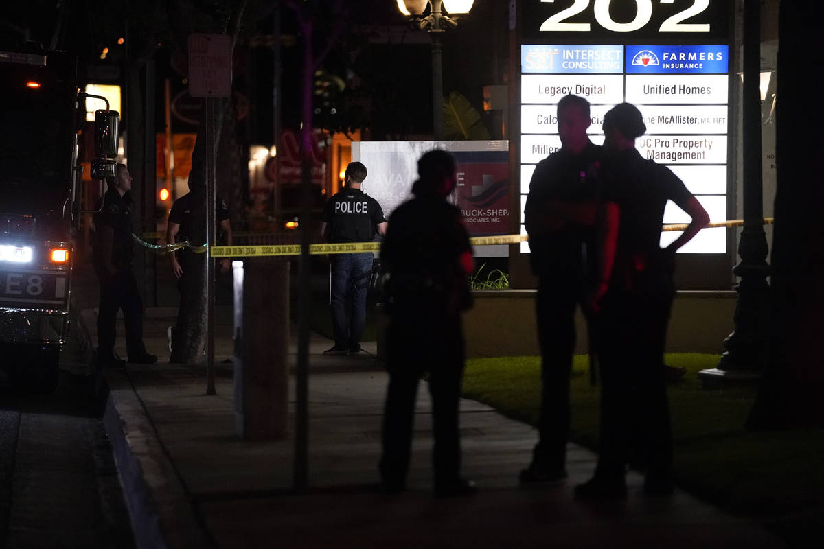Police officers stand outside a business building where a shooting occurred in Orange, Calif., ...